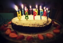 round Happy Birthday cake with lighted candles